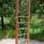 Vertical wooden ladder na hřišti obklopeném stromy.