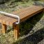 Gymnastic bench vyrobený z dřevěných latí s kovovým madlem ve venkovním prostředí.