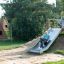 Dítě sjíždí po Hill Slide Wide h150 na hřišti.
