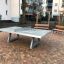 Concrete table tennis, free-standing na dlážděném dvoře s lavičkami v pozadí