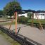 Swing Frame (double swing) na hřišti s dřevěnými nosnými trámy a pískovým povrchem.
