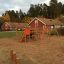 Panther wooden playhouse na hřišti se skluzavkami a lezeckými prvky.