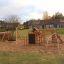 Panther wooden playhouse na pískovém hřišti s houpačkou a lezeckou stěnou.