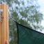 Sun Shade Triangle 5x5x5 Pioneer (Larchwood) připevněné k dřevěnému sloupku.