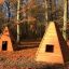 Dva Wigwam wooden house v podzimní lesní mýtině.