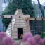 Wigwam wooden house na hřišti s růžovými květinami v popředí