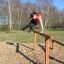 Žena skáče přes Double Jump Bars v parku.