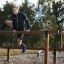 Sportovec přelézající přes venkovní fitness zařízení Double Jump Bars.