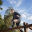 Muž šplhající na Climb Obstacle wooden ladder ve venkovním parku.