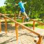 Osoba používající Climb Obstacle wooden ladder ve venkovním parku.