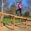 Žena leze na Climb Obstacle wooden ladder v parku.
