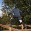 Muž šplhá po Climb Obstacle wooden ladder ve venkovním parku.