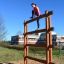 Žena šplhající po Step And Climb wooden ladder na venkovním hřišti.