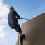 Muž šplhající na Climbing Ramp steel structure pomocí lana.