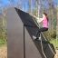 Žena šplhající na Climbing Ramp steel structure na venkovním hřišti.