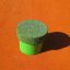 Zelený skákací kolík ze sady Jumping pegs (5 pcs.) na oranžovém povrchu.