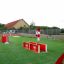 Venkovní herní vybavení Ball Catcher s červenými a bílými překážkami na zeleném hřišti.