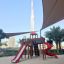 Herní vybavení Twister castle with slide v prostředí městského parku s Burj Khalifou v pozadí