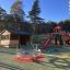 Twister castle with slide na hřišti obklopeném stromy a přístřeškem