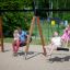 Double Swing (BNS 90cm) používané na hřišti s rodinami, které si užívají houpačky.
