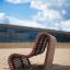 Sofa Wave, moderní venkovní dřevěná lavička na písčitém povrchu v městském prostředí.