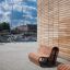 Venkovní dřevěné lavičky Sofa Wave poblíž moderní budovy s cihlovými zdmi.