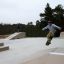 Skateboardista předvádějící trik na Jump-Ramp ve venkovním skateparku.