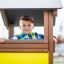 Dítě si hraje uvnitř Villa Maxi sandbox with a playhouse.