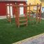 Chimpanzee wooden playhouse s lezeckými žebříky a tyčemi na zelené umělé trávě.