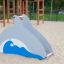 Hřišťová skluzavka Dolphin Slide ve tvaru delfína na pískovém hřišti.