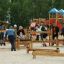 Děti a dospělí si venku hrají na Balance herním prvku na hřišti.