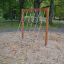 V-shape Net wooden playhouse v písčité herní oblasti obklopené stromy.