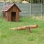 Nature Playhouse na travnaté zahradě s dřevěnou houpačkou.