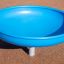 Modré hřištní vybavení Flying Saucer na písčitém povrchu.