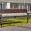 Oxford Bench, moderní parková lavička z tmavého dřeva s kovovým rámem v městském prostředí.