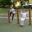 Dvě děti si venku hrají na Somersault Double herním prvku