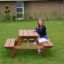 Larchwood Table & Bench for Kids s dívkou sedící na lavičce v zahradním prostředí