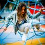 Dítě lezoucí po Powerclimber climbing net, modrá lanová prolézačka na dětském hřišti.